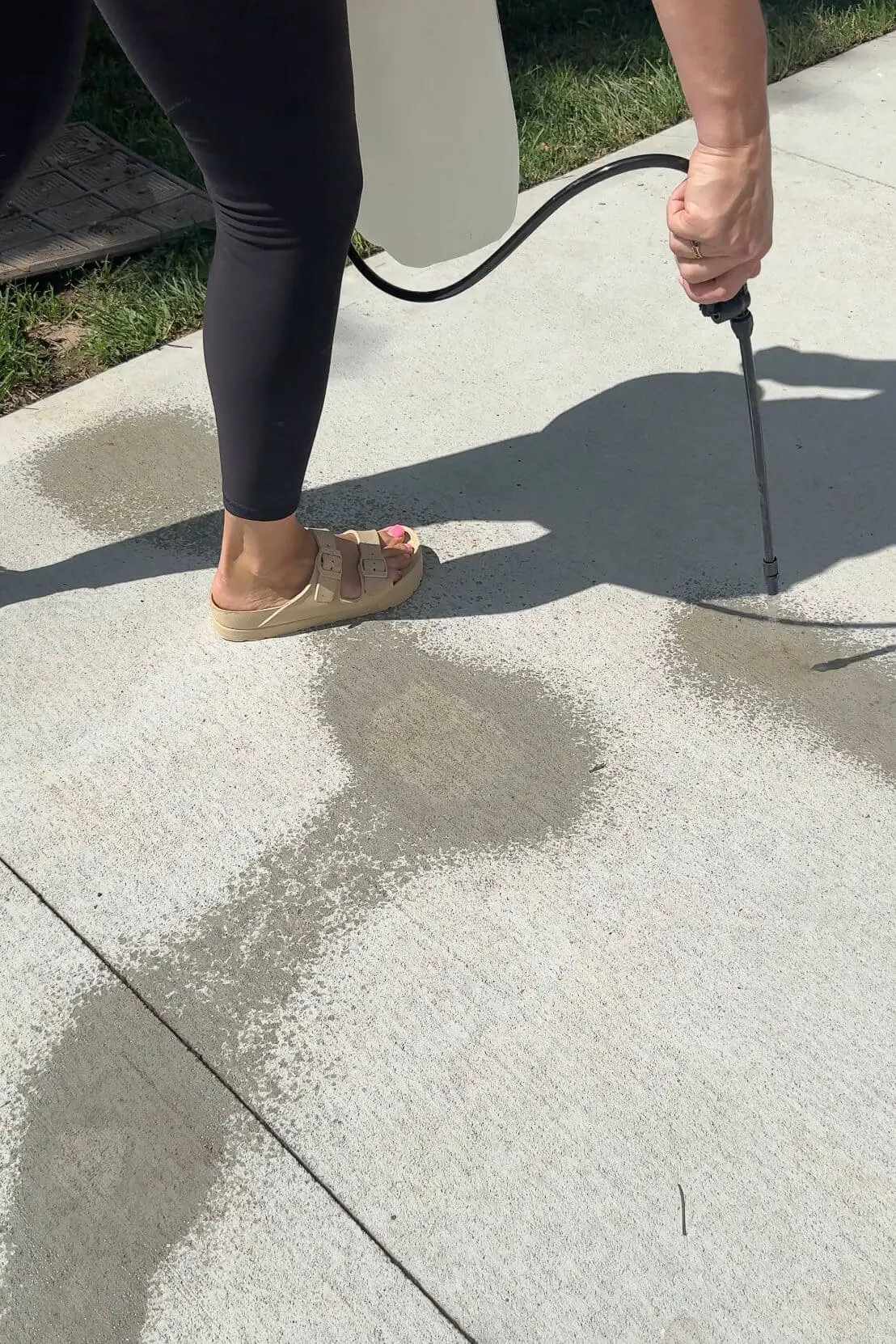 Spraying bleach solution onto patio with handheld pump sprayer