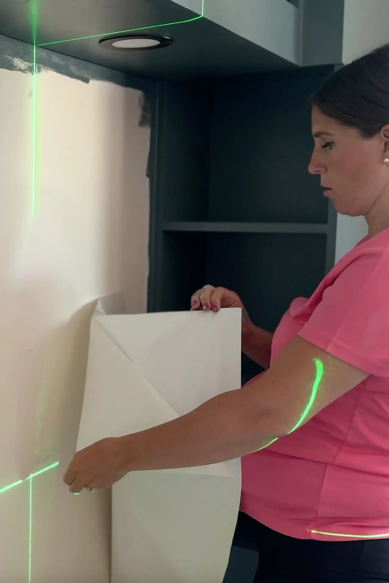 Peeling the backing off plaid peel and stick wallpaper to start applying it to the wall.