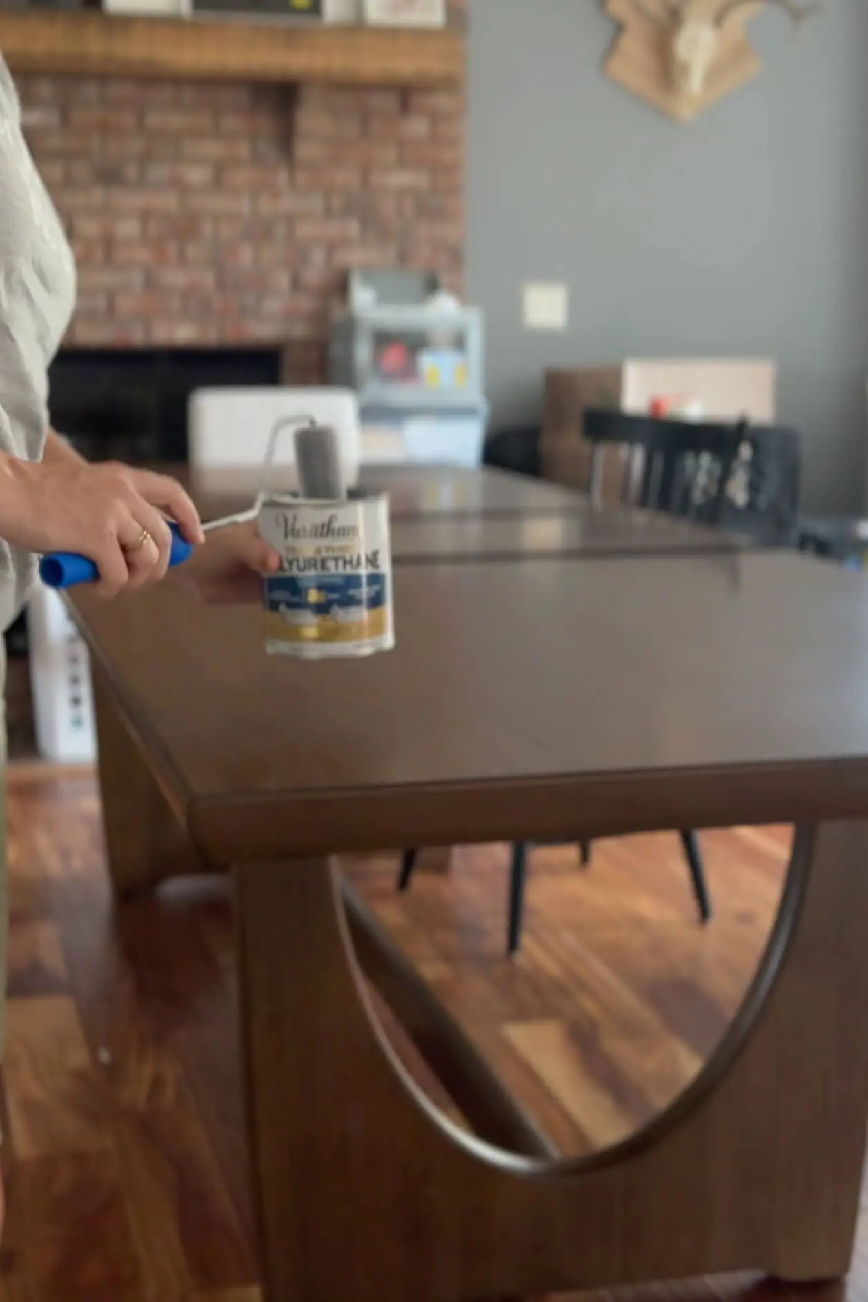 Applying polyurethane using a foam roller, with a can of Varathane in hand.