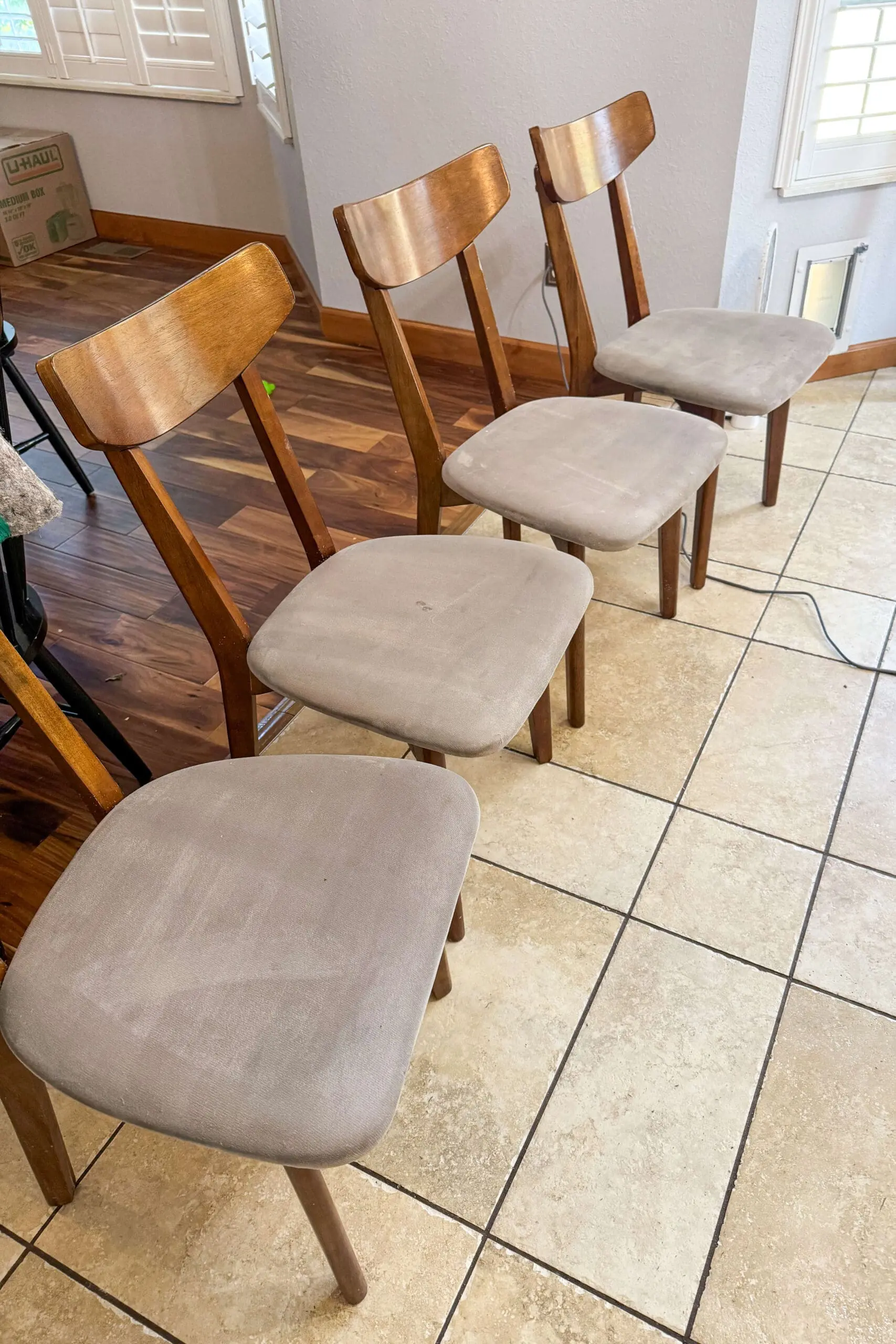 Set of four clean upholstered dining chairs with smooth beige fabric and wood backs, shown after upholstery cleaning.