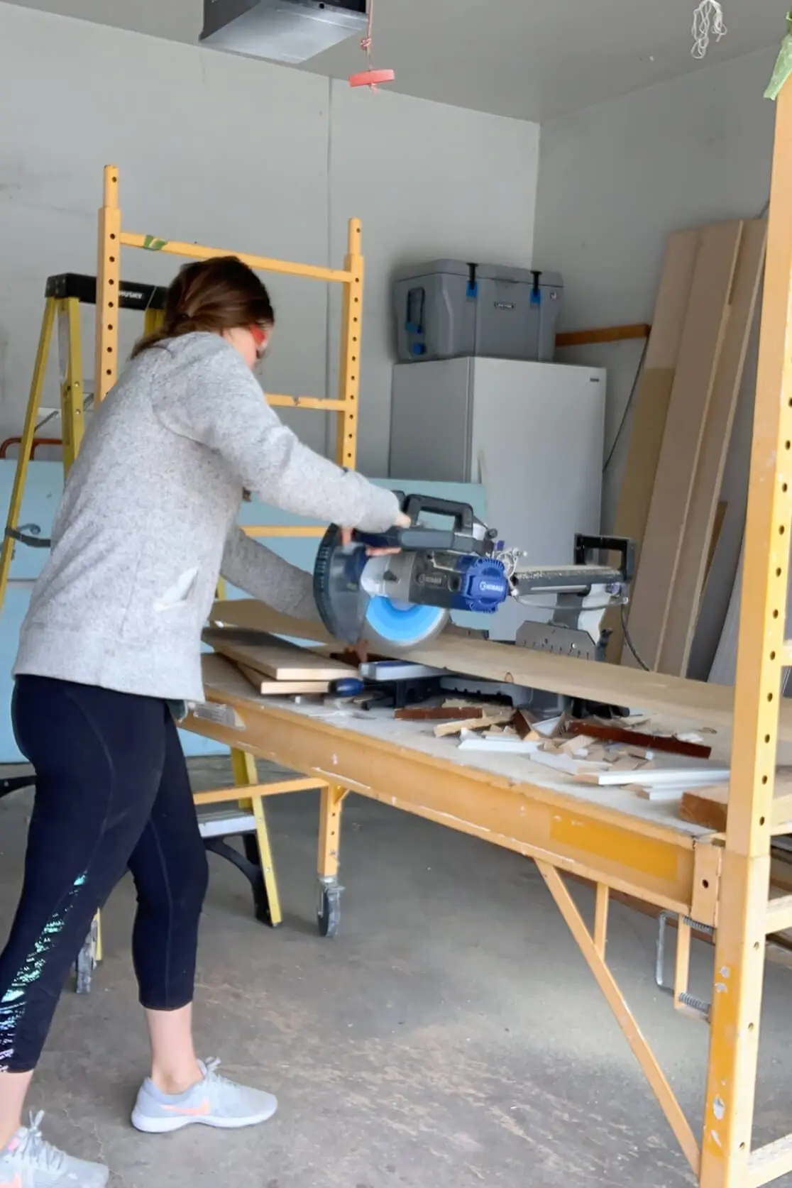 Cutting wood boards to length with a sliding miter saw inside a garage workspace during a DIY build.