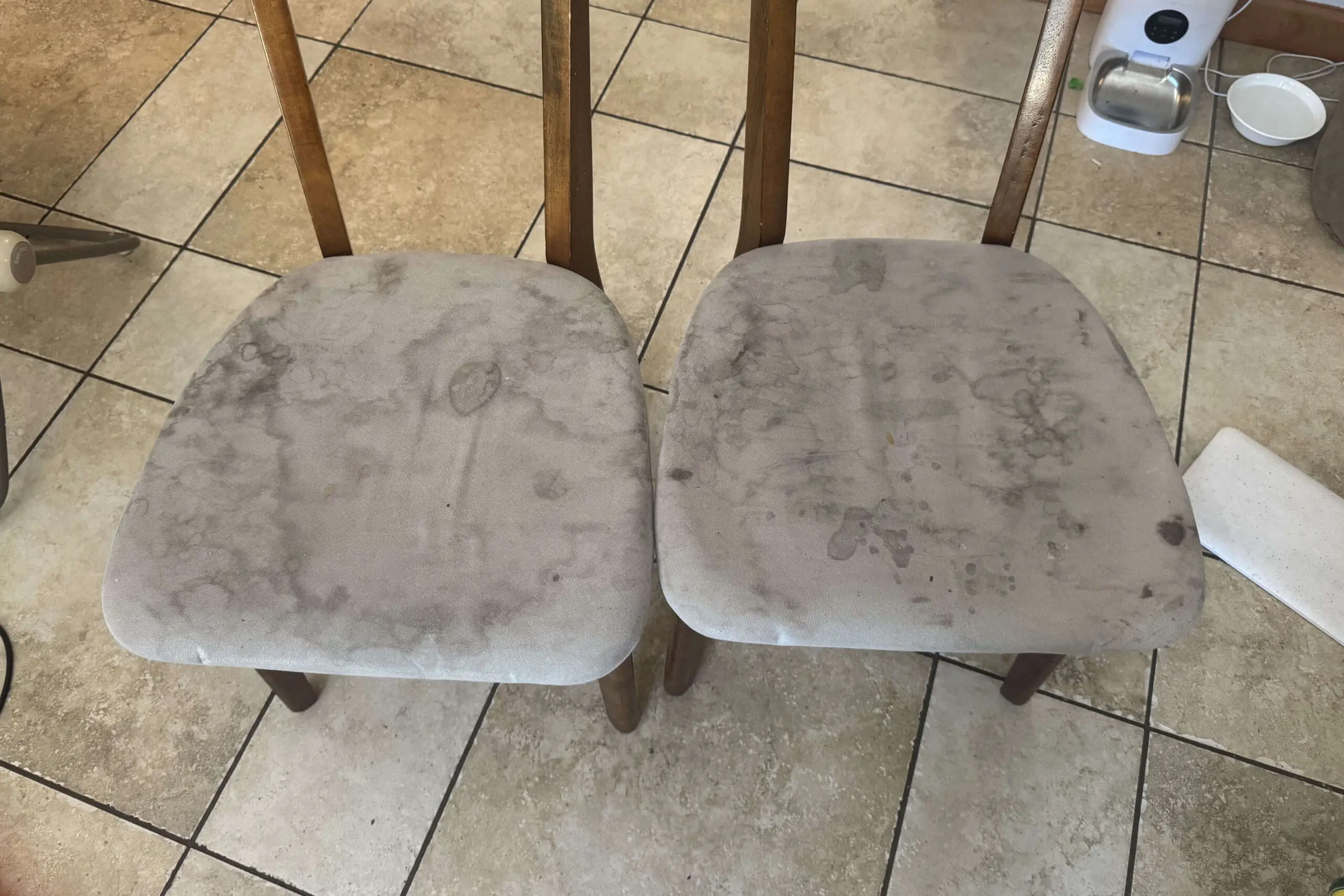 Two heavily stained upholstered seats with dark marks and water spots before.