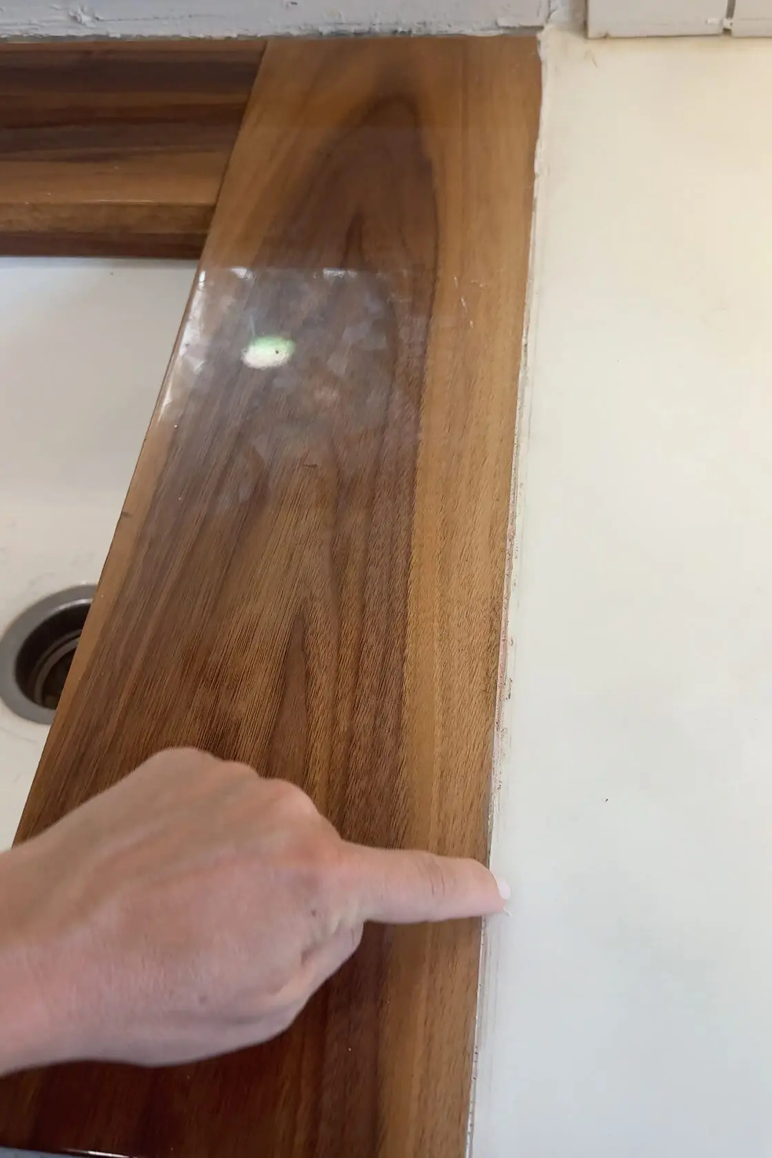 Close-up of finger pointing to the seam between wood counters and faux marble counters.