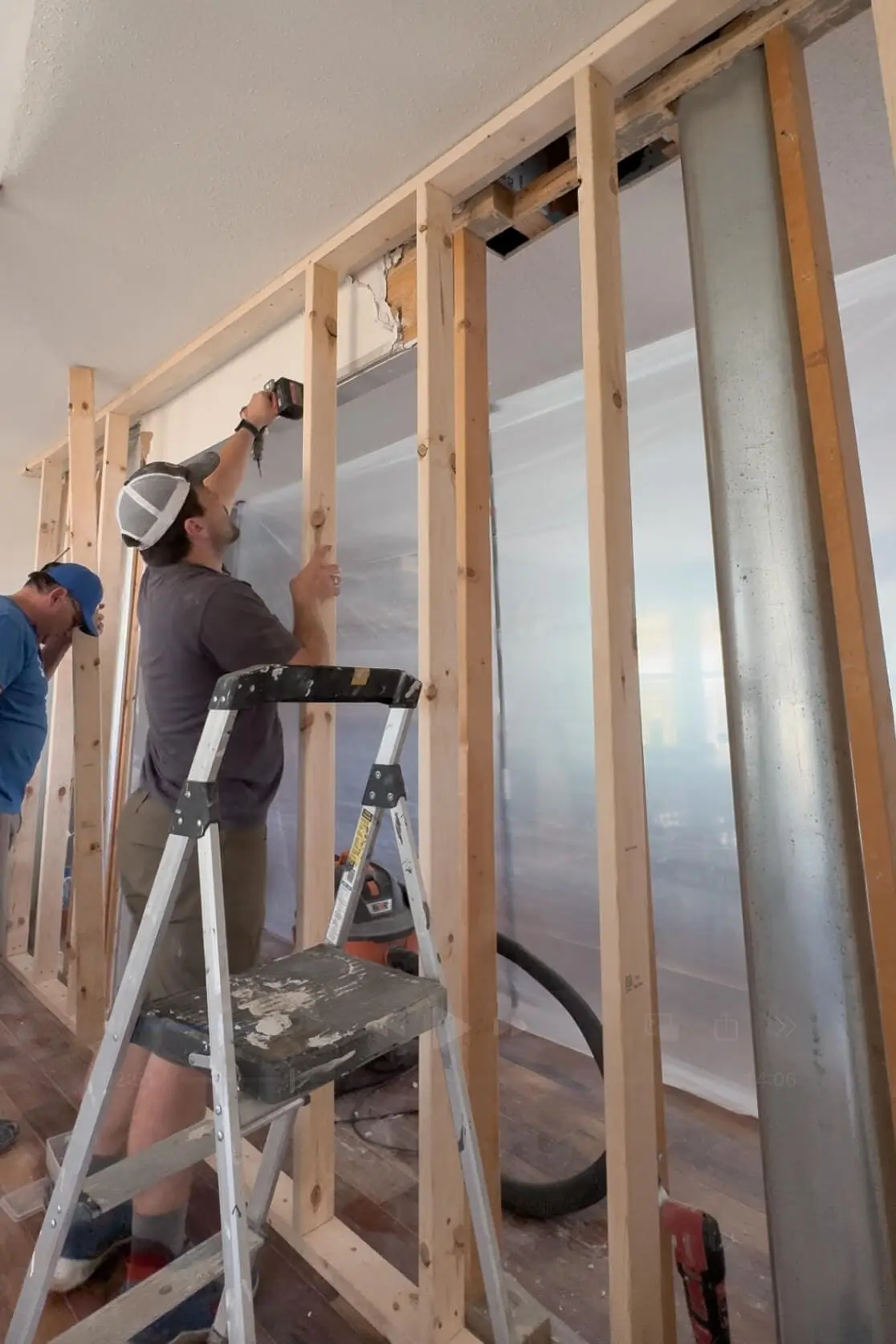 Two people framing a new interior wall during a major DIY renovation in a newly purchased home, showing the start of transformation plans.

