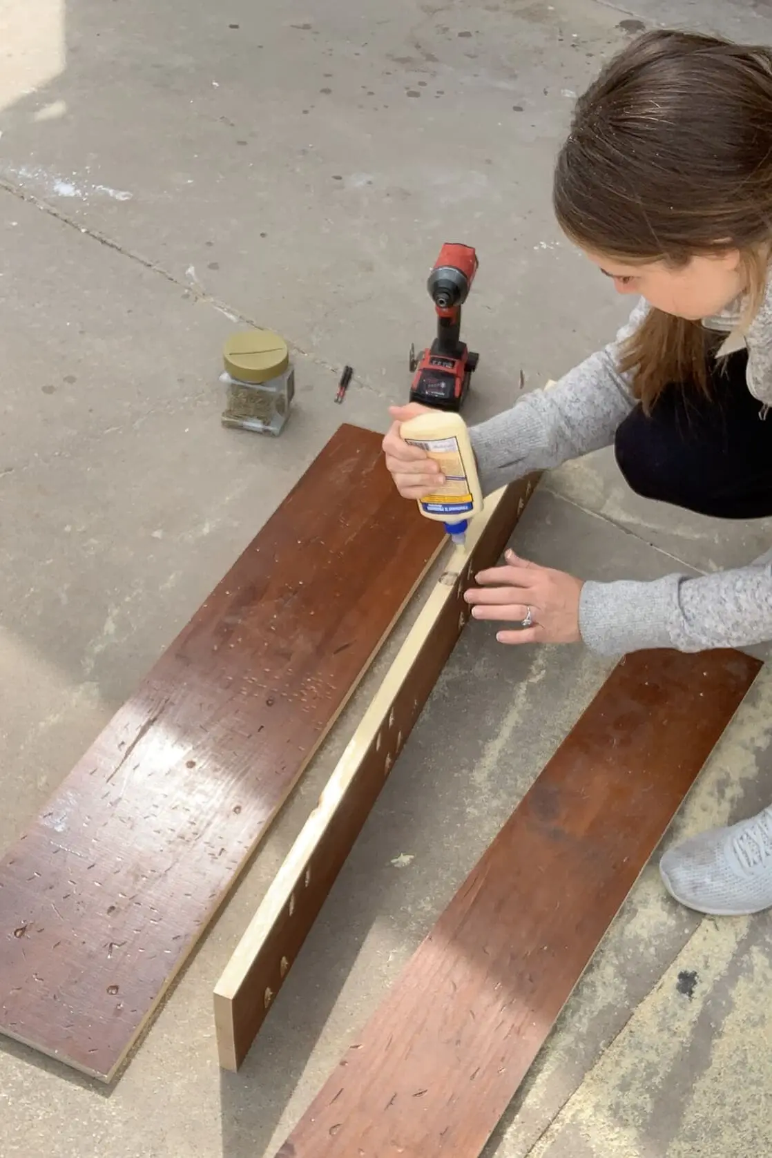 Applying wood glue to repurposed mantel boards before clamping and joining them for a tabletop build.