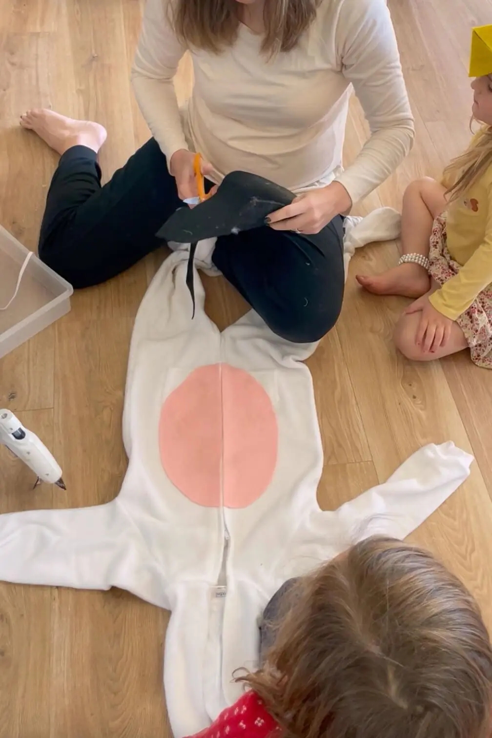 Cutting black felt spots to attach to a white jumpsuit while making a homemade Halloween costume.