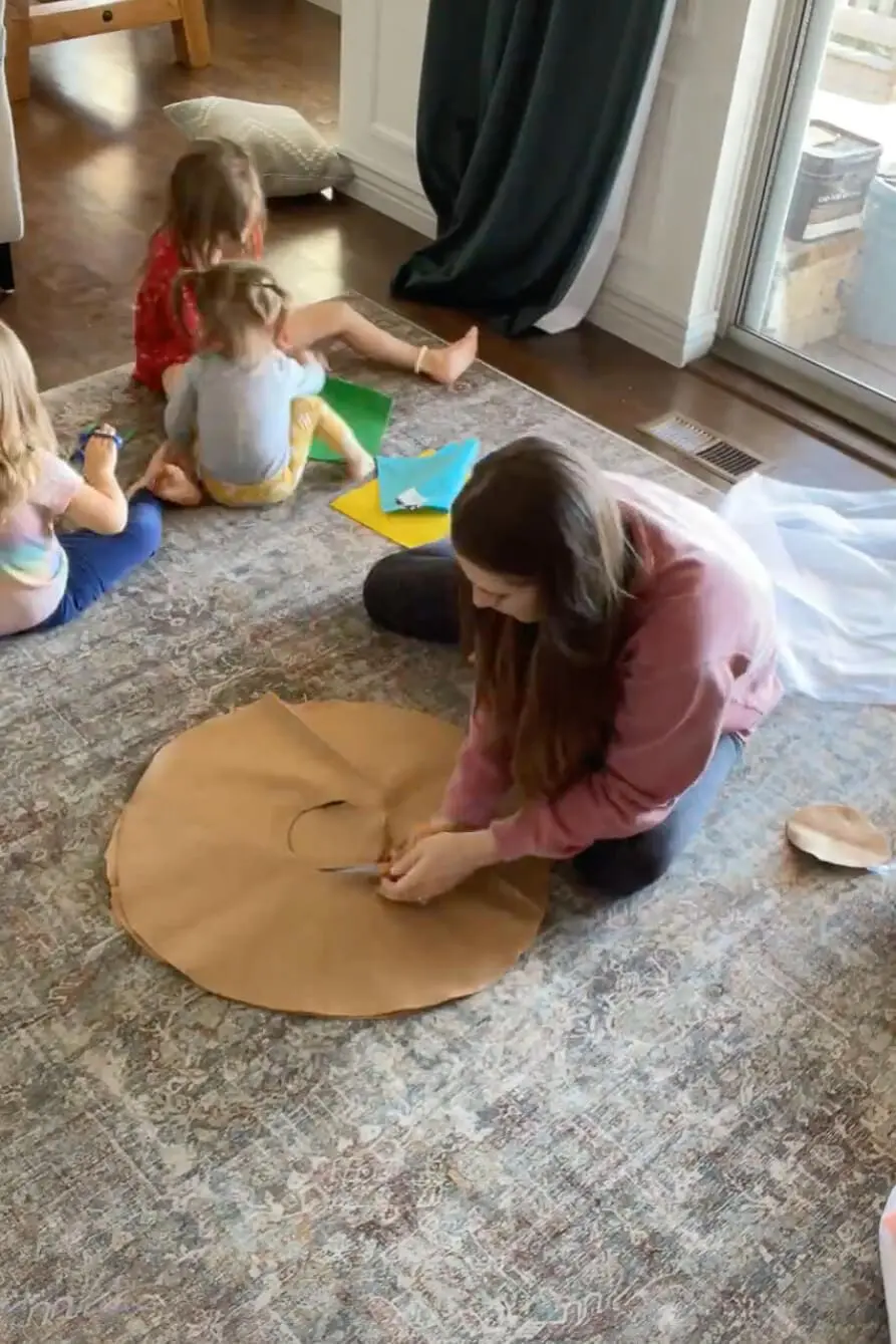 Cutting a large brown fabric circle to form the base of a DIY donut pillow.