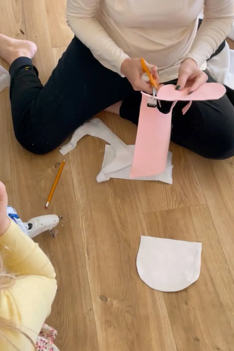 Cutting nostril openings into pink felt for the muzzle of a DIY cow costume mask.
