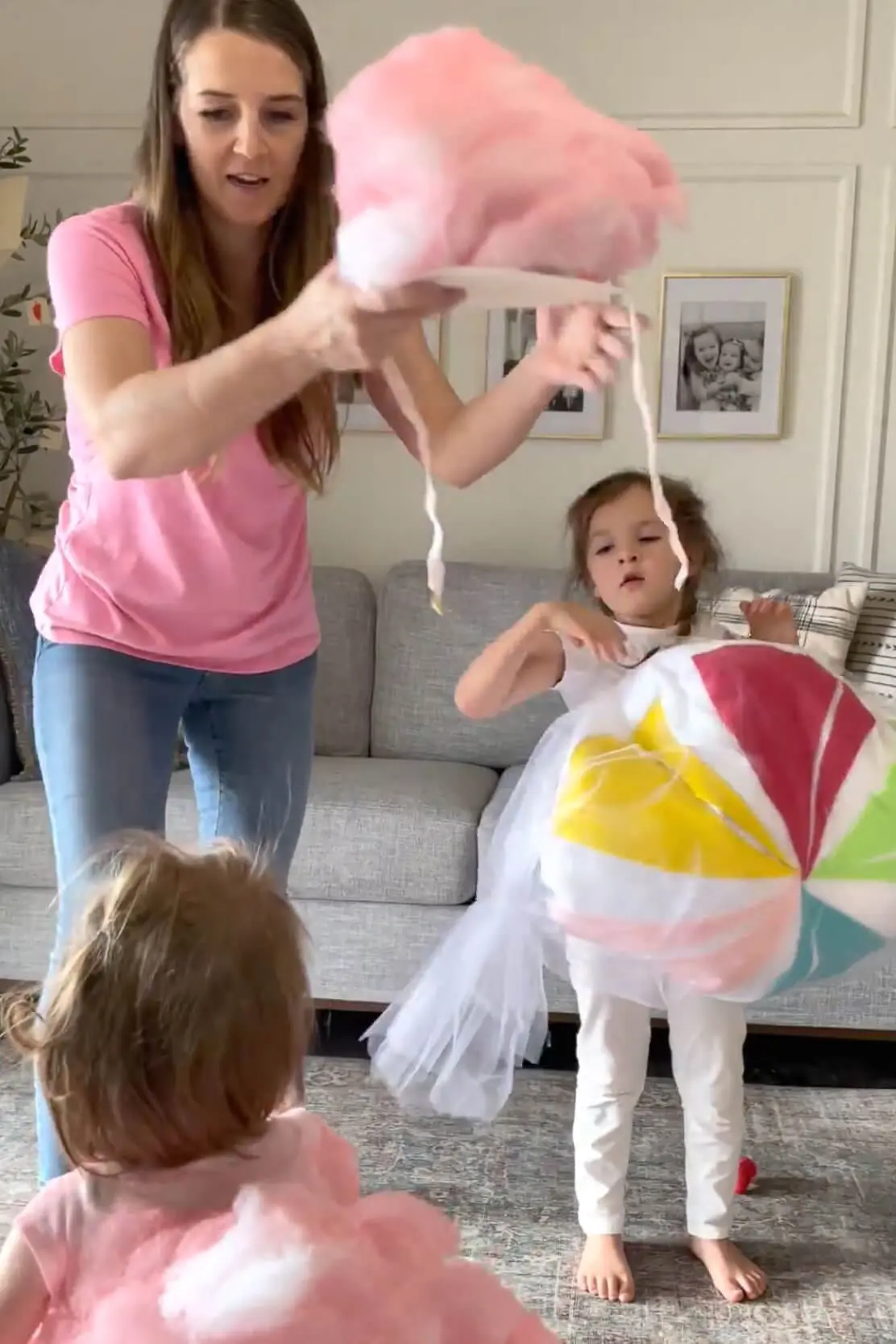Mom holding a pink fluffy headpiece while kids wear colorful dress up outfits.