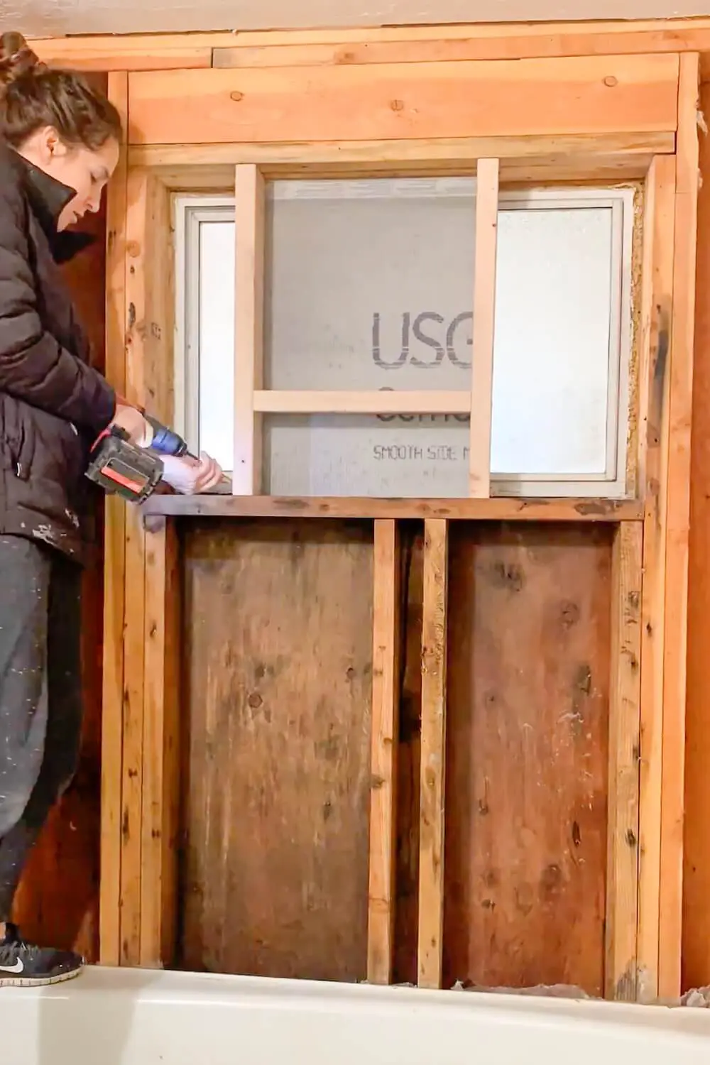 Securing the shower niche frame by screwing it into the right wall stud during installation.