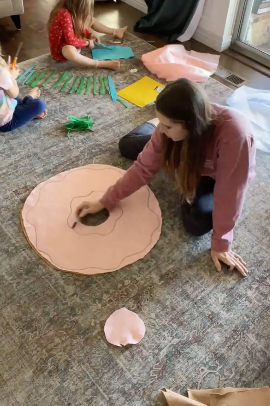 Drawing a wavy frosting outline on pink fabric for a handmade donut pillow.