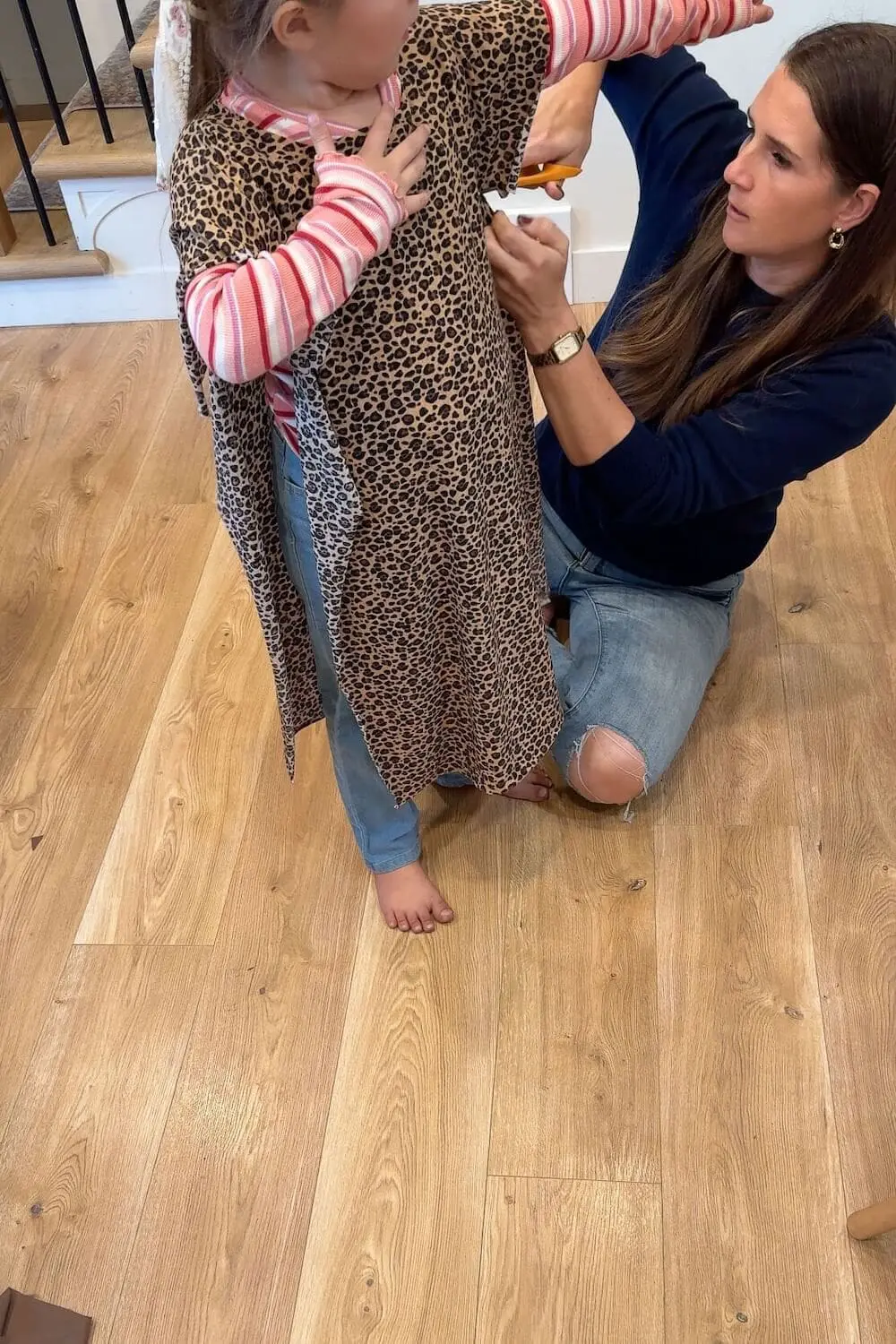 Making DIY caveman costumes for family costume ideas, cutting leopard print fabric for a child’s outfit