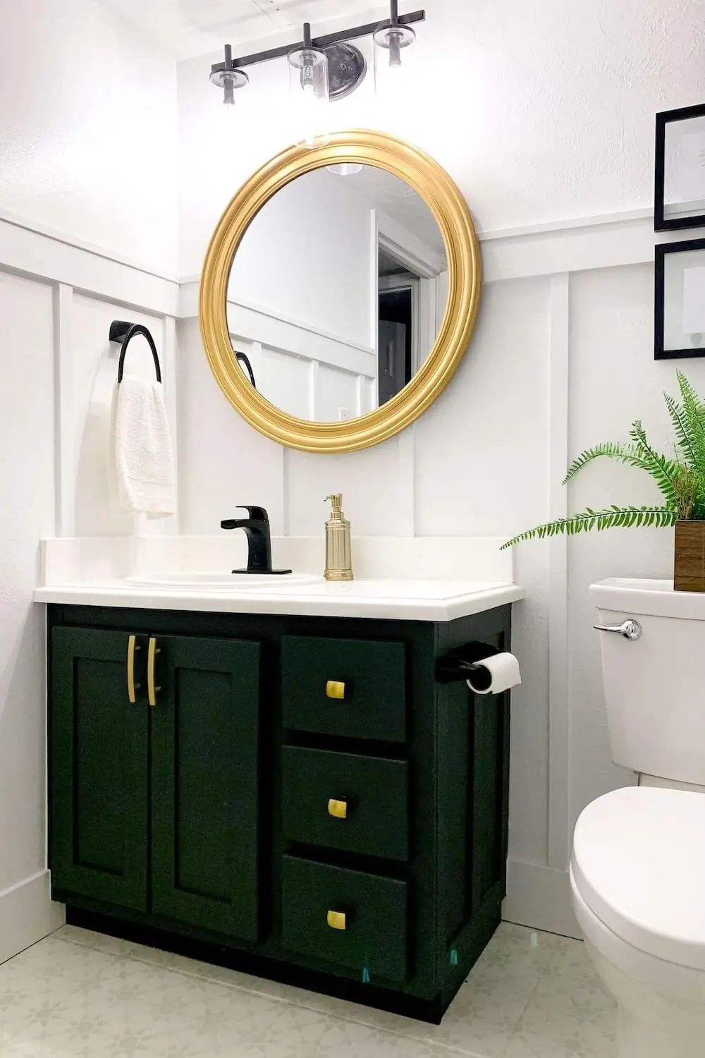 Modern small basement bathroom remodel with dark green vanity, round gold mirror, white subway tile shower, and patterned tile floor.