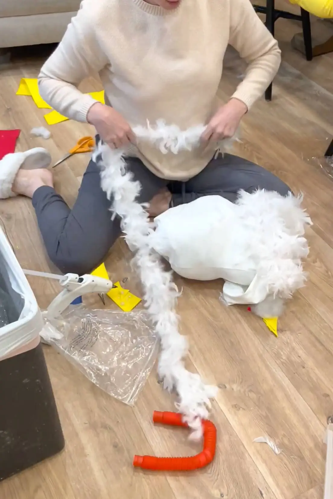 Making a DIY chicken costume by attaching white feather boas to a hoodie with hot glue for an easy no-sew Halloween costume project.