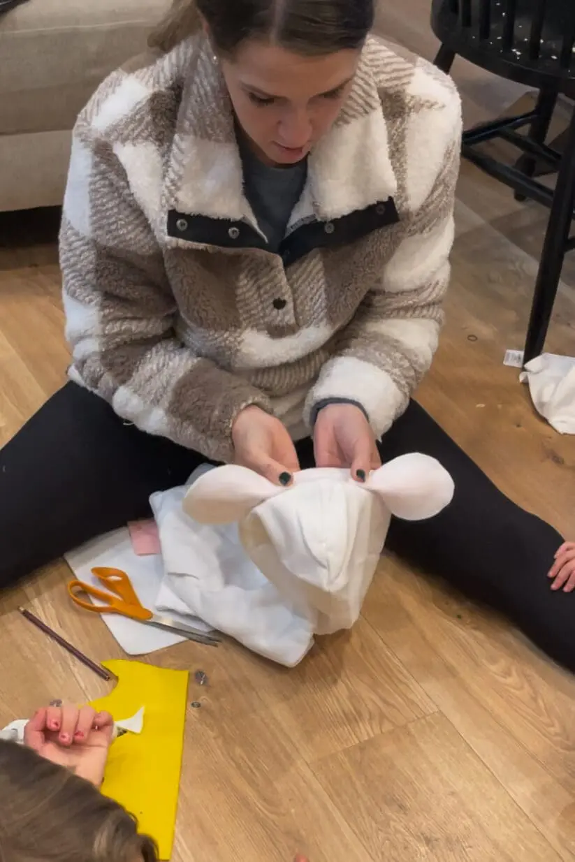 Making a no sew sheep outfit by attaching felt sheep ears to a white hoodie.