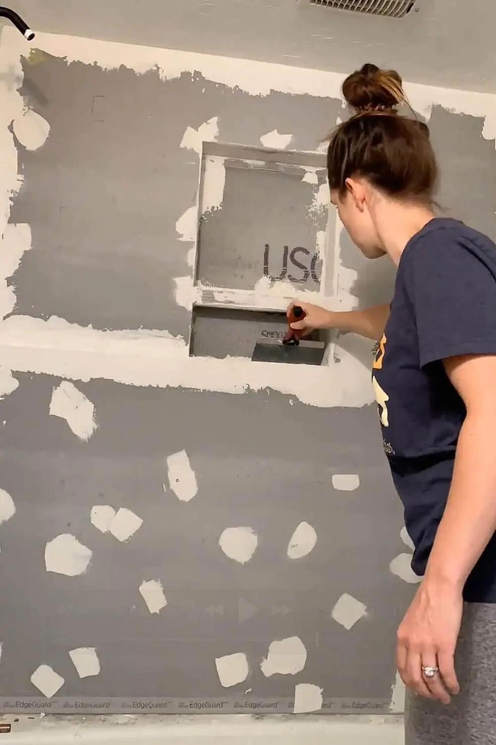 Alkali-resistant mesh tape and thinset reinforcing the corners and seams of a shower niche.