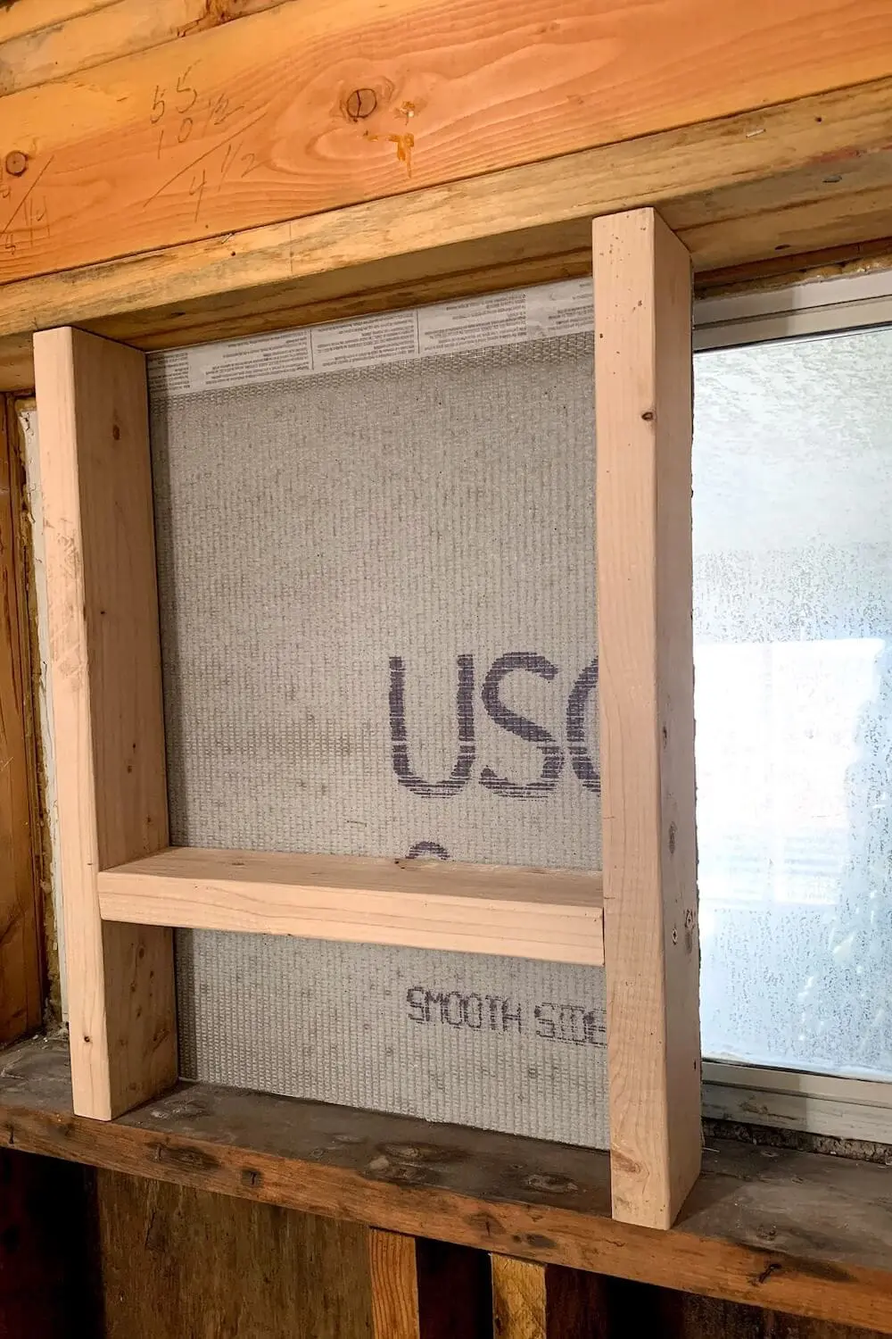 Close-up of a framed shower niche installed between wall studs during bathroom demolition and prep.