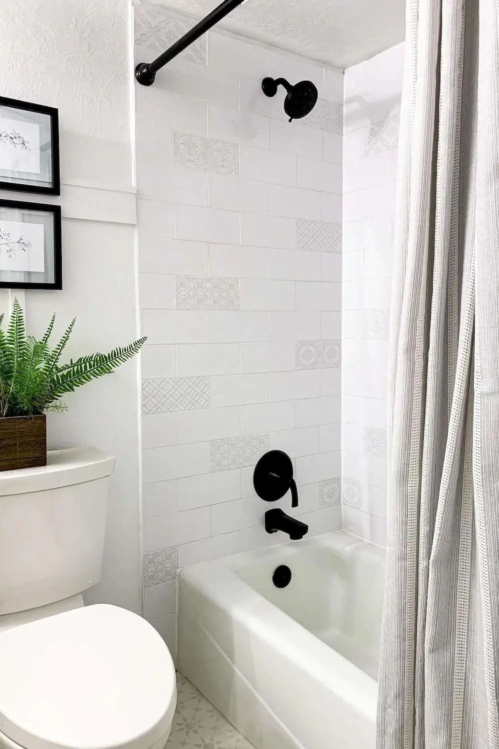 Finished white subway tile shower with double niche featuring patterned backs and matte black fixtures.