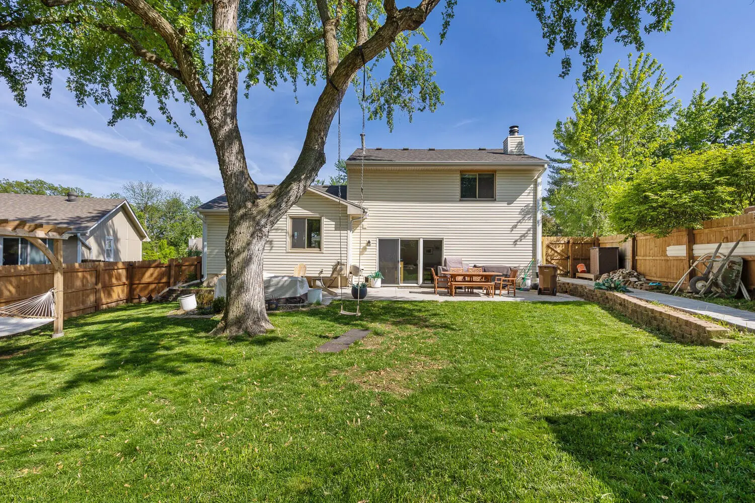 backyard remodel after with new patio, Adirondack chairs, and landscaping