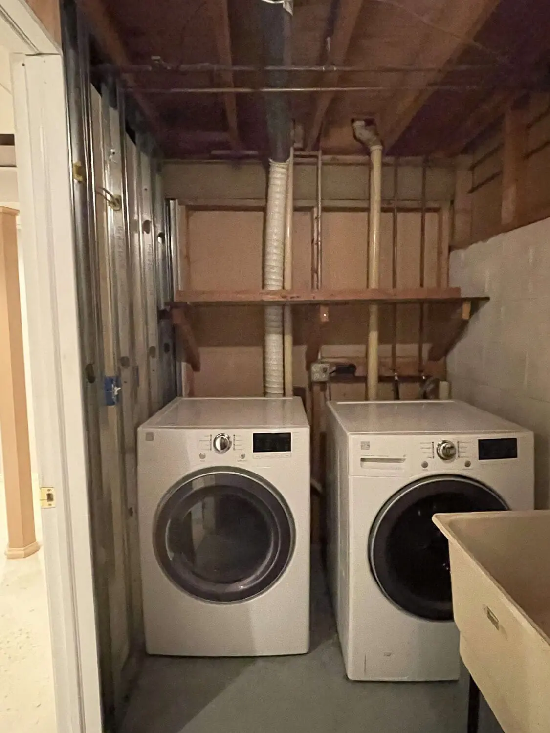 Basement laundry room before DIY home renovation with exposed pipes and unfinished walls.