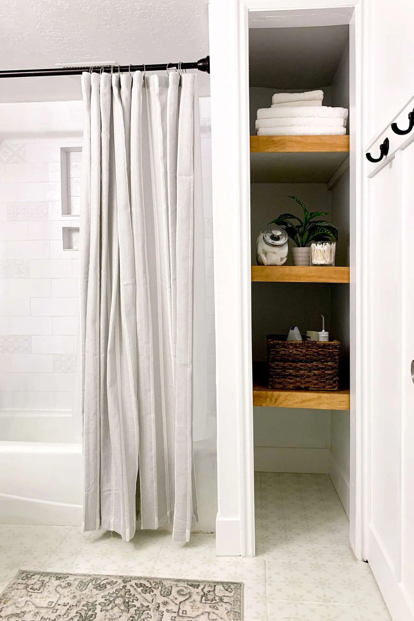 Bathtub and shower area with white subway tile surround, black fixtures, and gray curtain next to painted floor.