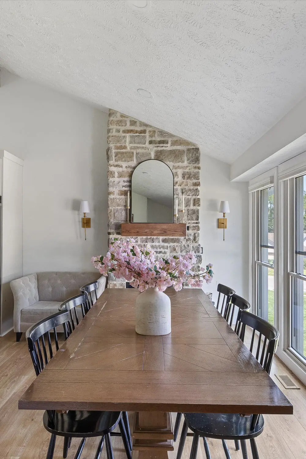 dining room after remodel with stone fireplace, sconces, and large windows