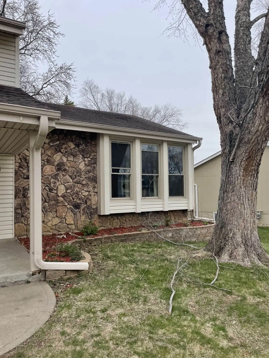 Split-level home before DIY home renovation with outdated siding and stone accent