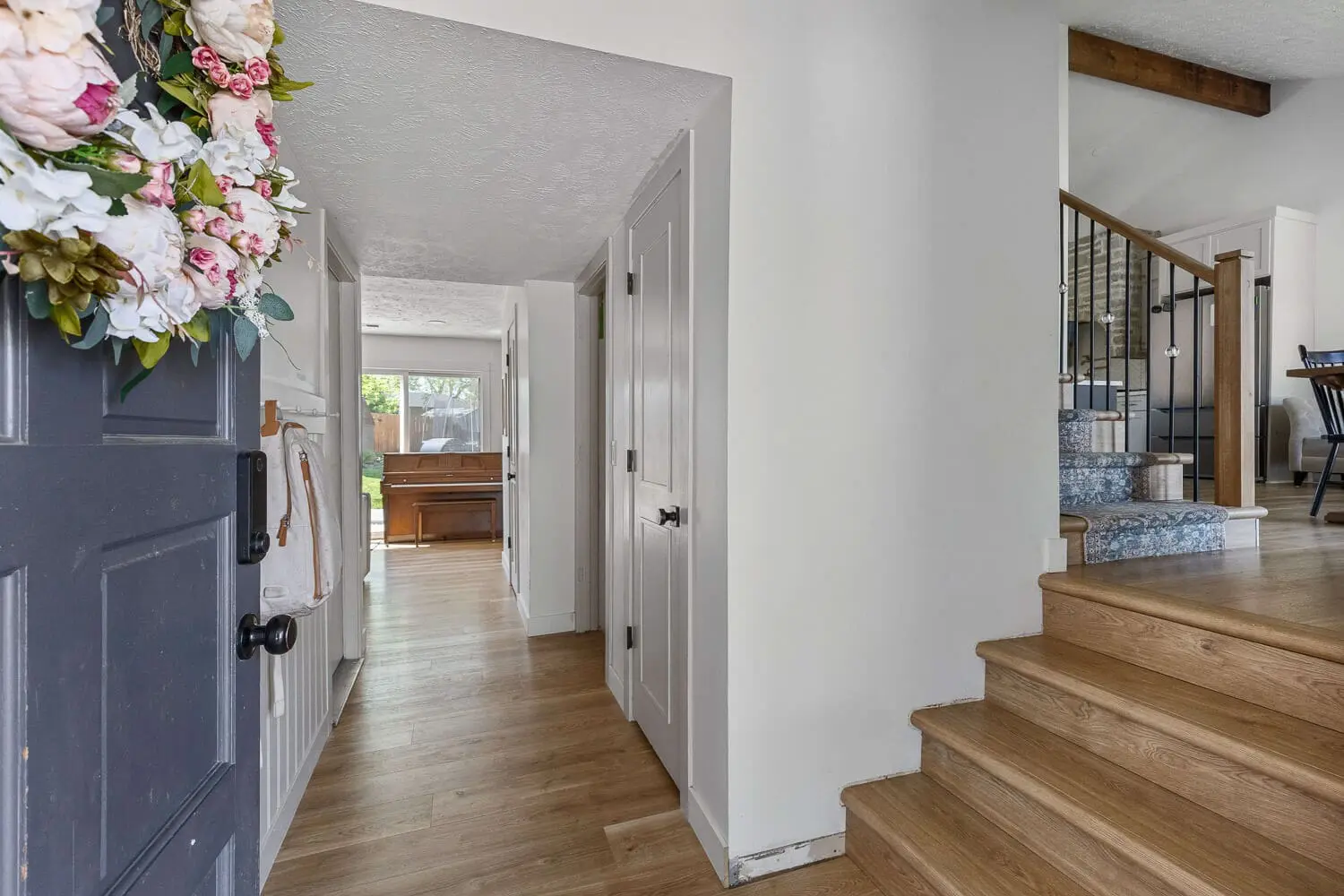 freshly remodeled entryway with white walls, wood floors, and staircase view
