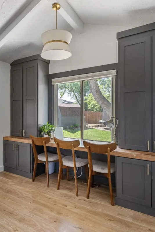 home office after remodel with dark built-ins, wood desktop, and three chairs