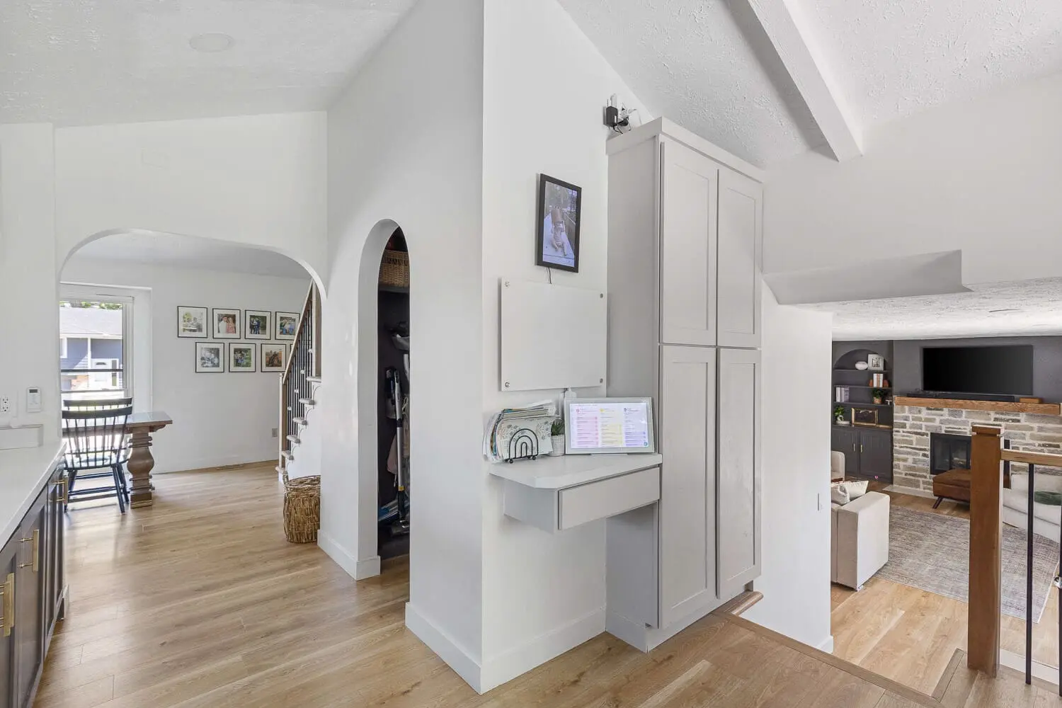 hall command center with slim built-in cabinet, small desk, and arched pantry nook