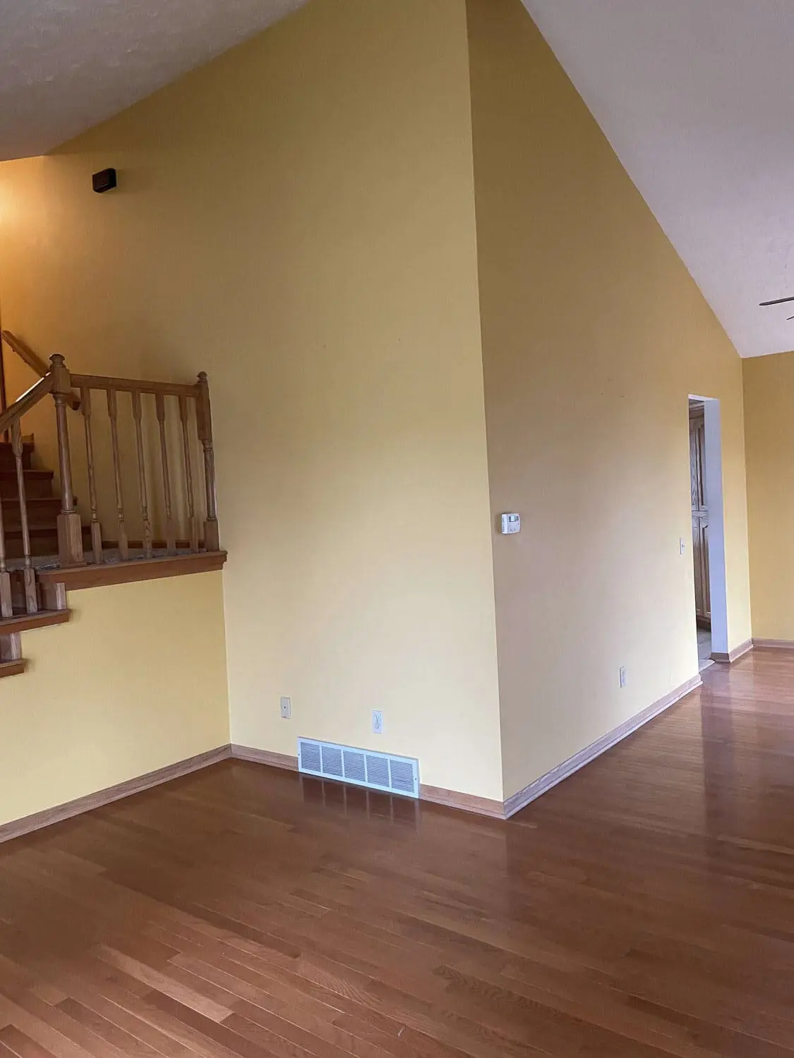 living room before renovation, yellow walls and dated railings by stairs
