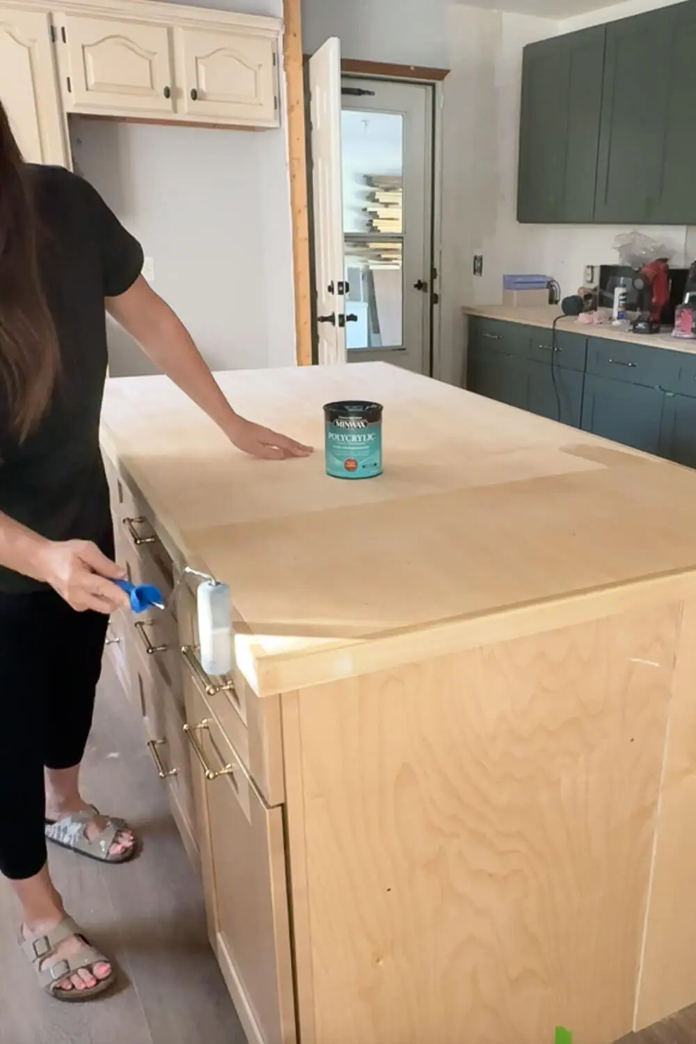 Applying polycrylic sealer with a foam roller to prep plywood kitchen island countertop for faux marble contact paper wrap.