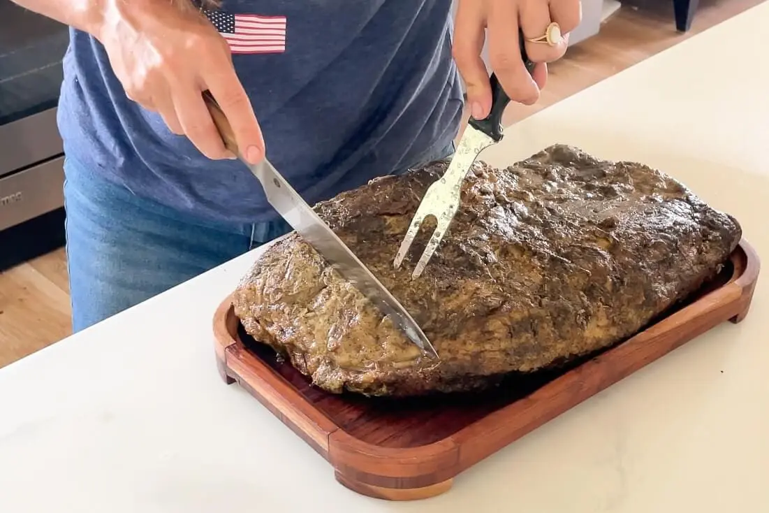 Slicing smoked brisket, a flavorful meat option for your game day food spread.