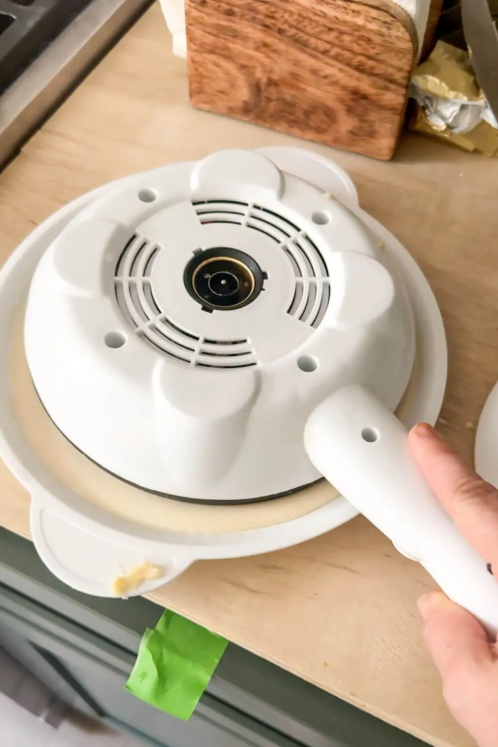 Electric crepe maker inverted into the batter tray, thin layer coating the nonstick plate for fast crepes.