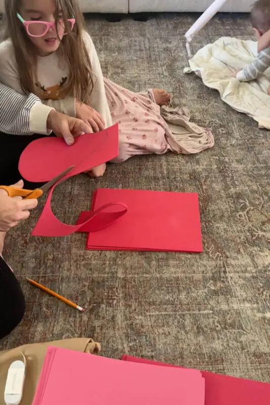 Cutting the traced petal from red cardstock to make layered petals for a quick, inexpensive no sew flower costume DIY.