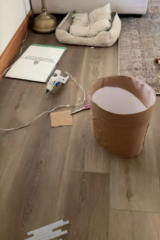 Finished terracotta-pot skirt wrapped in brown fabric, hot glue gun and scissors nearby, part of a kids DIY Halloween dress up.