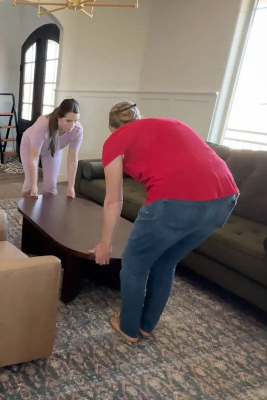 Setting an oval wood coffee table between the green velvet sofa and leather chairs in a formal living room seating area.
