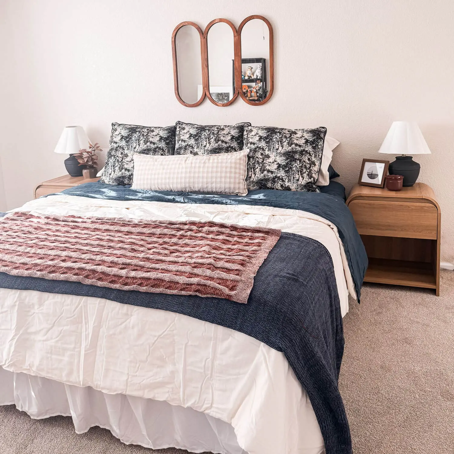 guest room refresh with cozy fall bedding, layered quilt and duvet, rust knit throw, plaid lumbar pillow, matching wood nightstands with lamps, triple wood mirror.