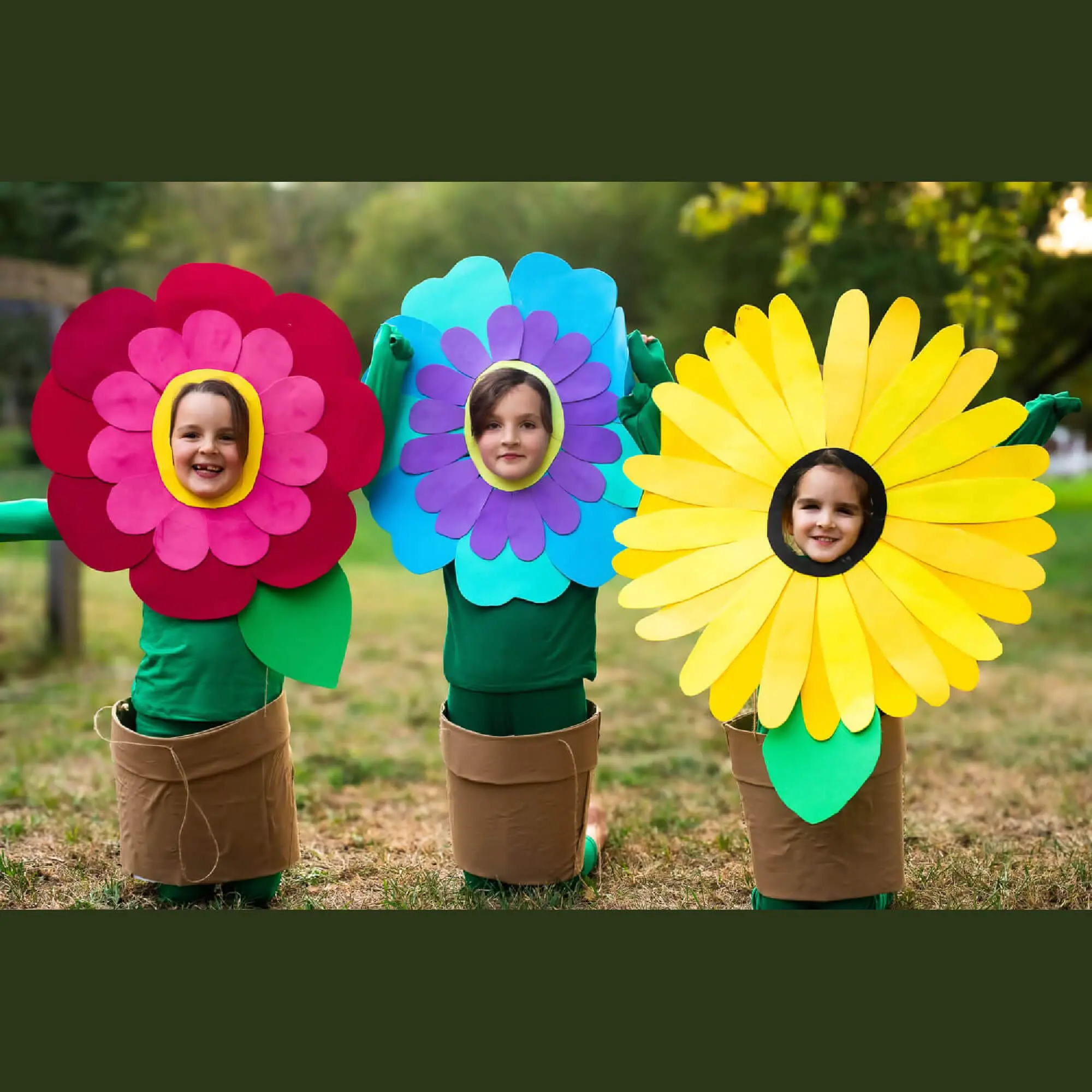 Three kids in no-sew flower costumes with layered cardstock petals—red, blue, and yellow—wearing green outfits and brown flower-pot skirts; quick, inexpensive DIY Halloween flower costume idea for kids.