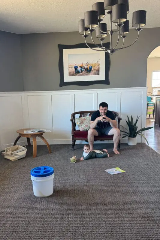 Formal living room before photo with dark gray walls, white board and batten, empty seating area, and brushed nickel chandelier