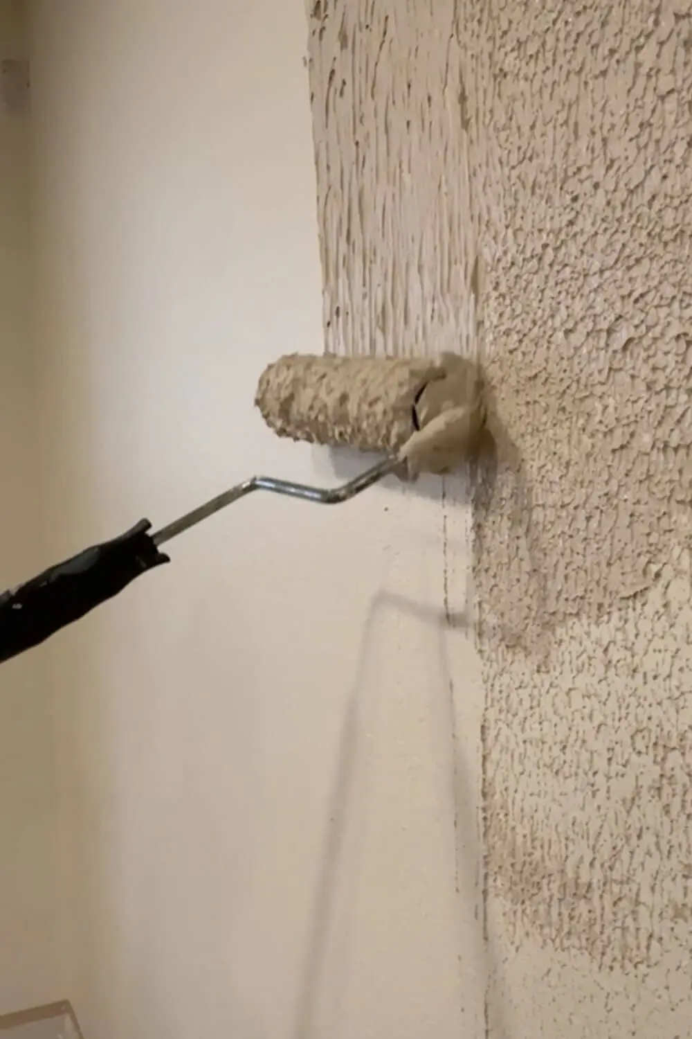 Rolling joint compound onto a textured wall to start skim coating and fill in the heavy texture before smoothing it flat
