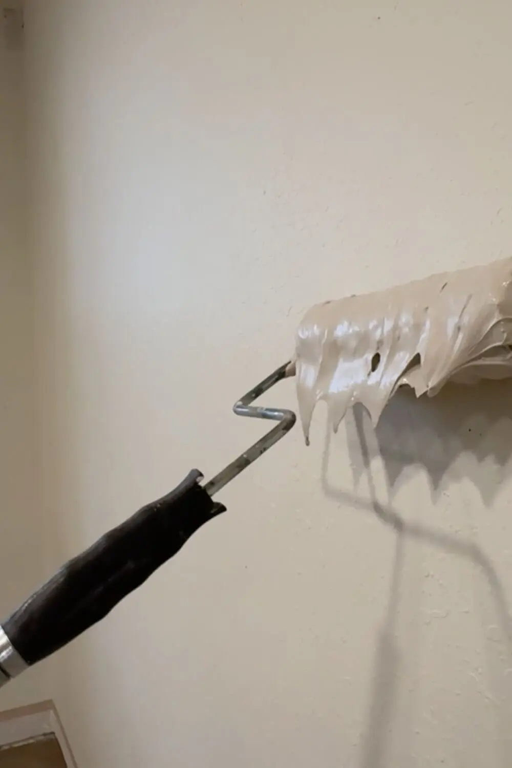 Close-up of a paint roller loaded with joint compound for skim coating a wall and covering texture before trowel smoothing