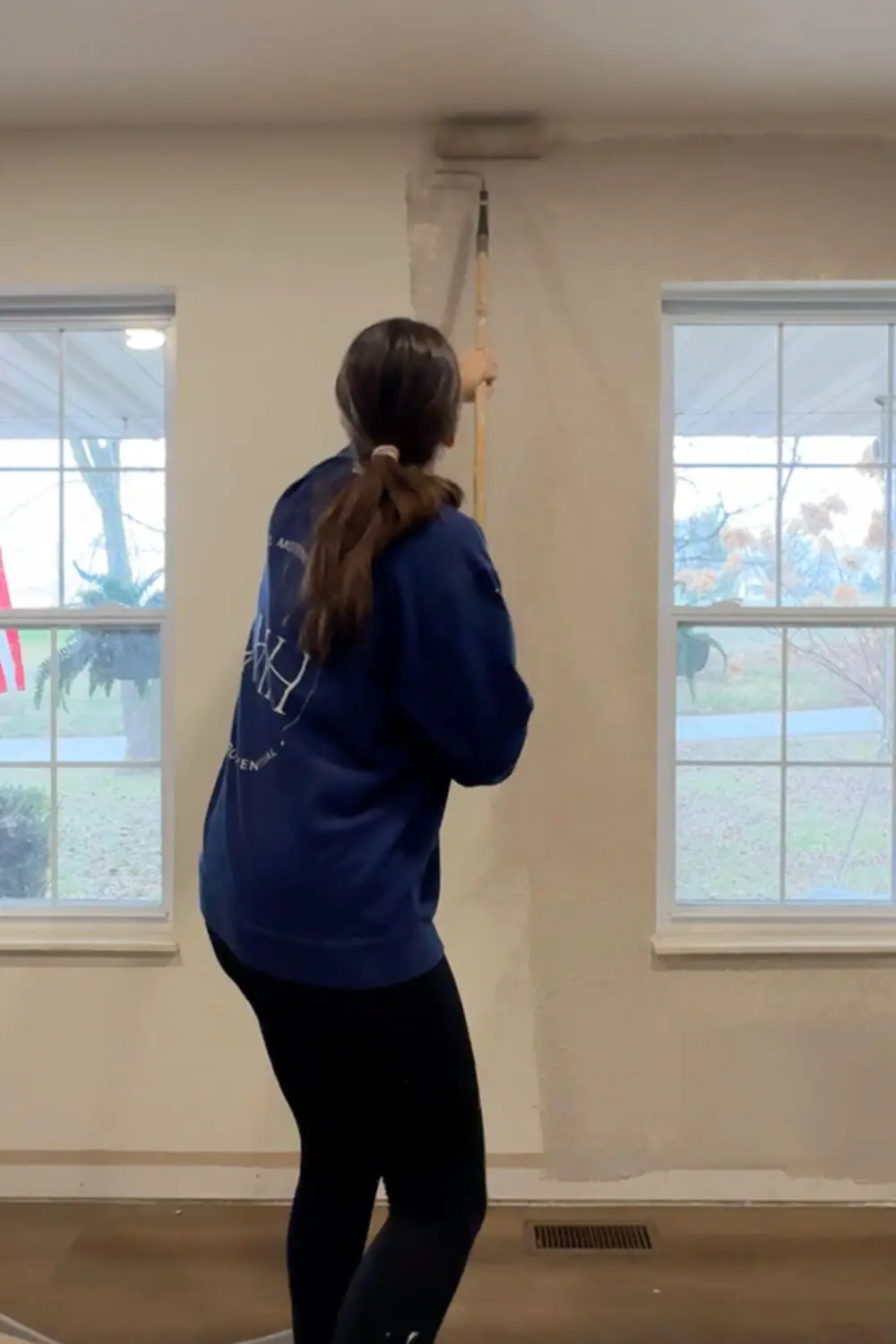 Rolling joint compound onto a wall to prep for skim coating, covering textured drywall before smoothing with a trowel