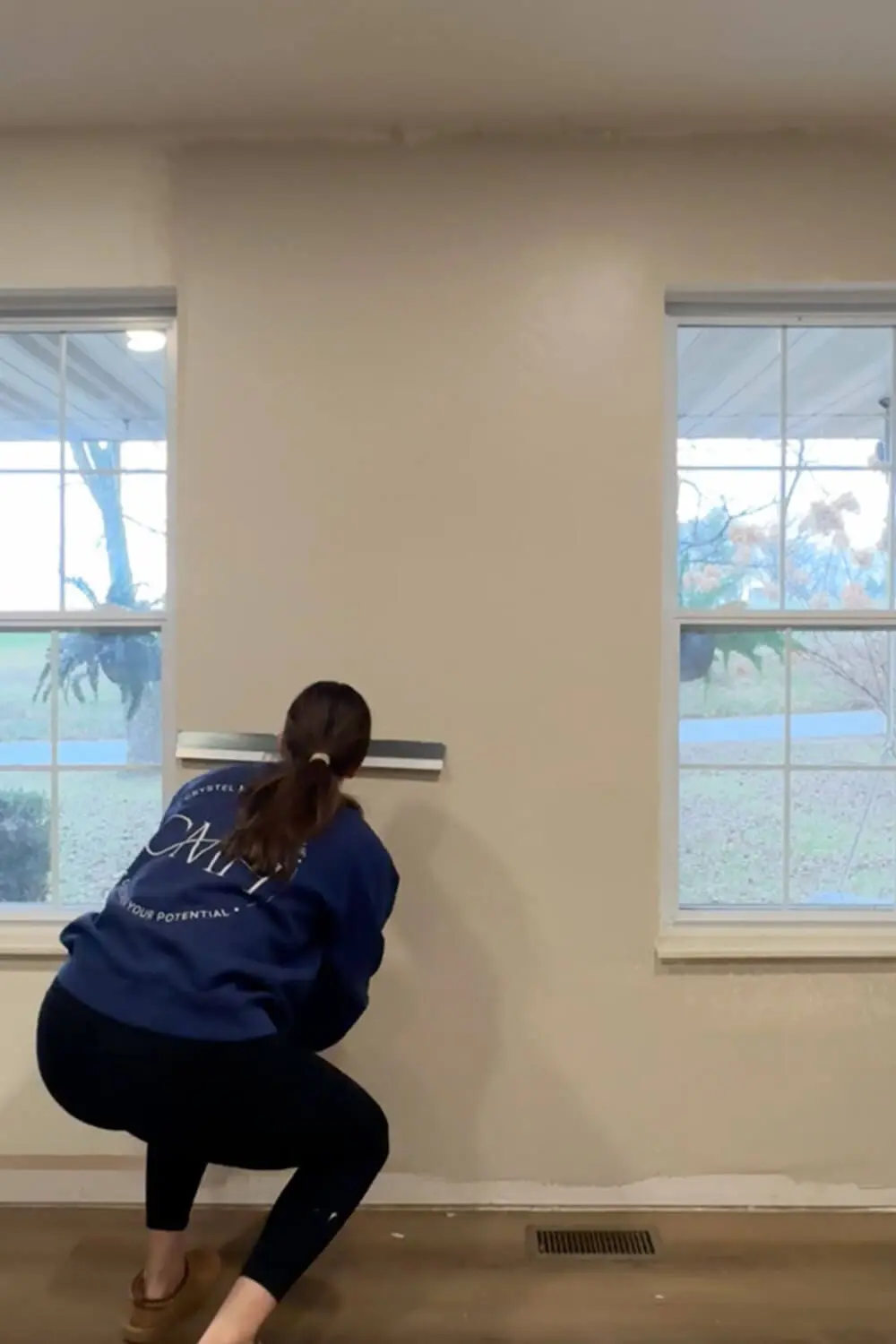 Skim coating a wall by pulling a wide drywall trowel over rolled-on joint compound to flatten texture and smooth the surface