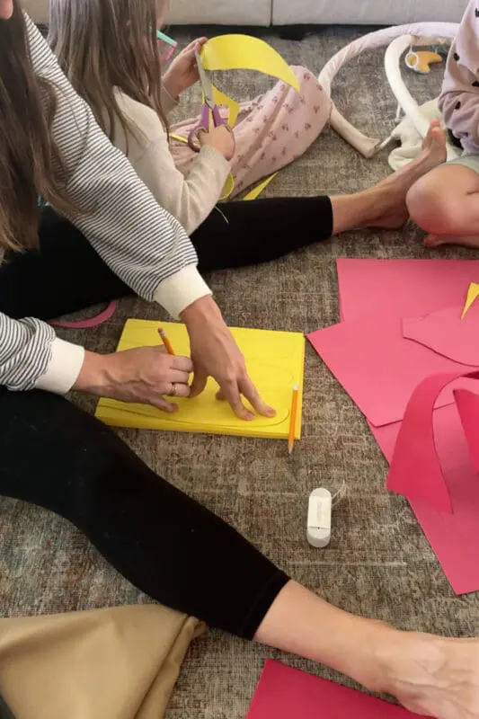 Tracing oval petals on stacked yellow cardstock with a pencil template to make layered petals for an easy, inexpensive no-sew flower costume.