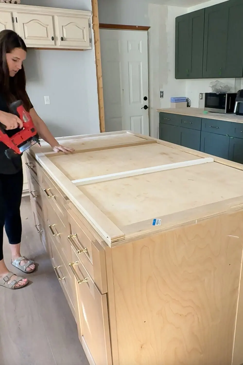 Attaching wood trim to a large plywood kitchen island while building DIY countertops, creating a thick edge profile before wrapping the island in faux marble and epoxy.