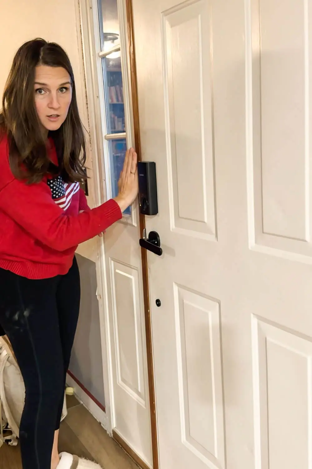 DIY blogger pressing new clear weatherstripping along the side of a white front door to seal out drafts