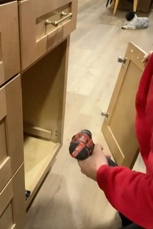 Removing the original door to place an insert for the garbage bin.