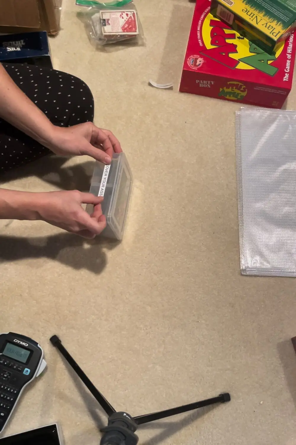 Labeling a plastic case for a card game, using a label maker to keep game neat, stackable, and easy to find.