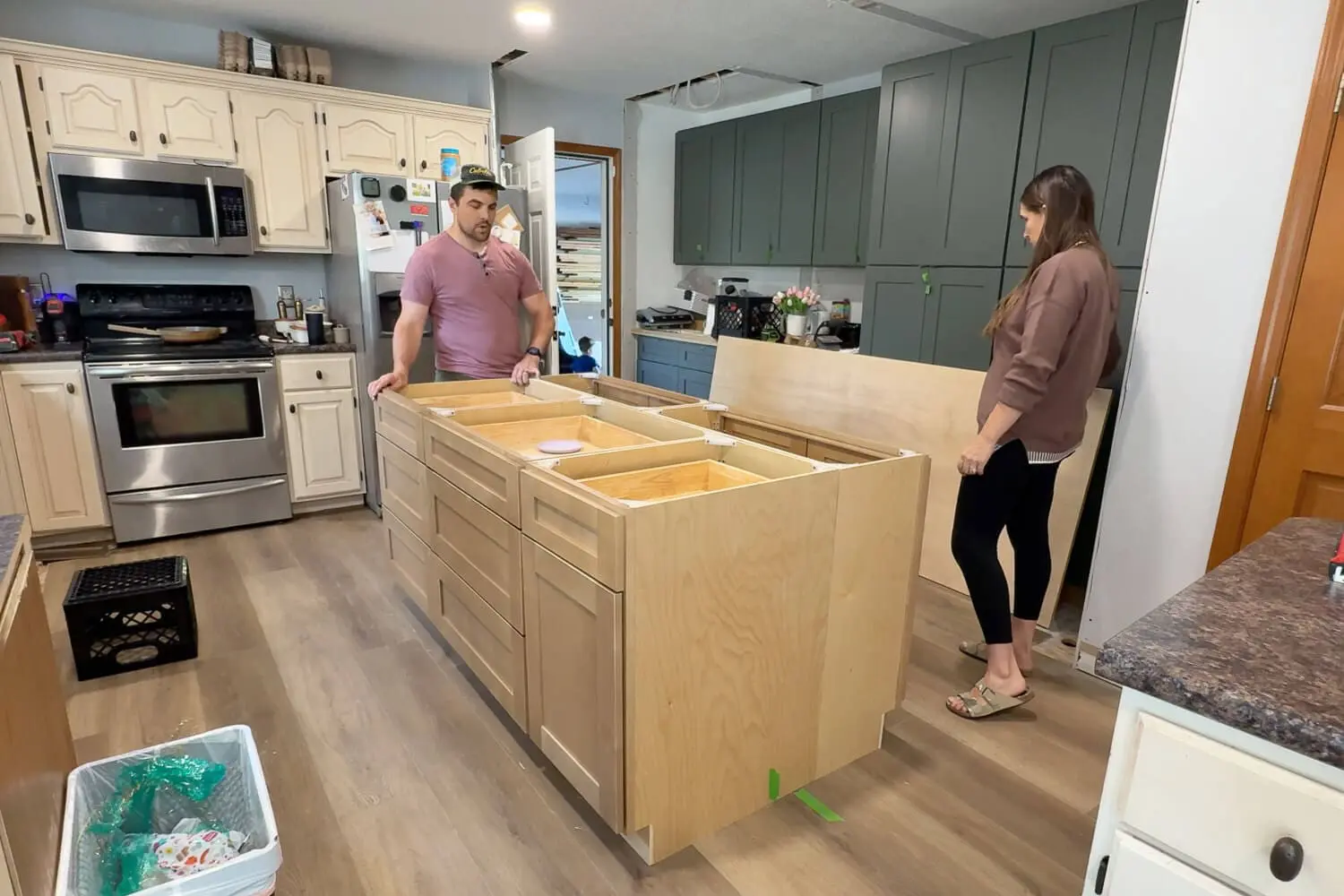 Laying out and assembling cabinet boxes to create a custom kitchen island during our DIY kitchen renovation, with the old kitchen still in the background.